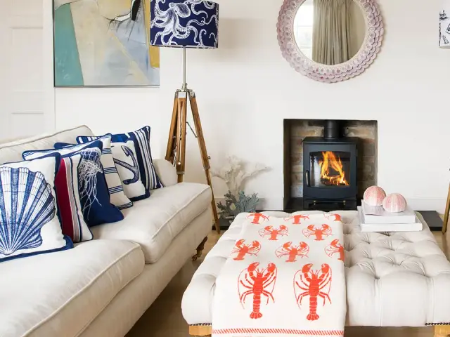 A living room styled with Cream Cornwall coastal-print lampshades, cushions and a lobster throw