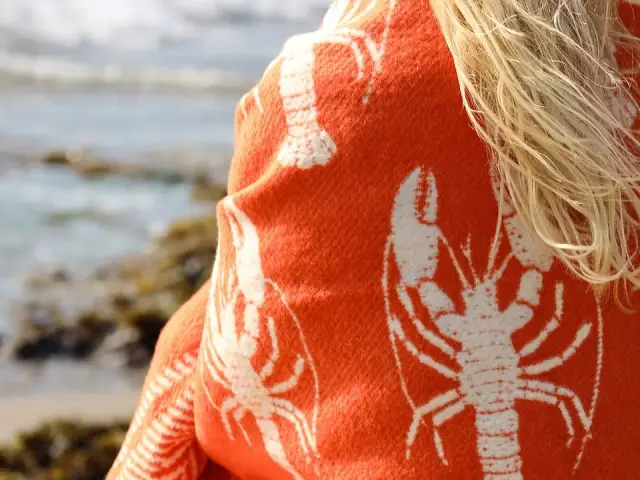 A Cream Cornwall lobster-print blanket worn on the beach