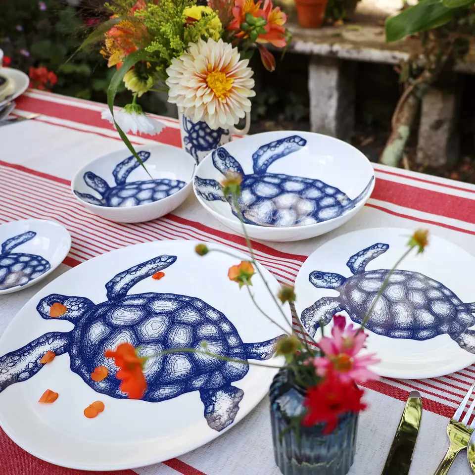 Blue and white turtle-print bone china bowls on a red-striped cloth, with garden flowers
