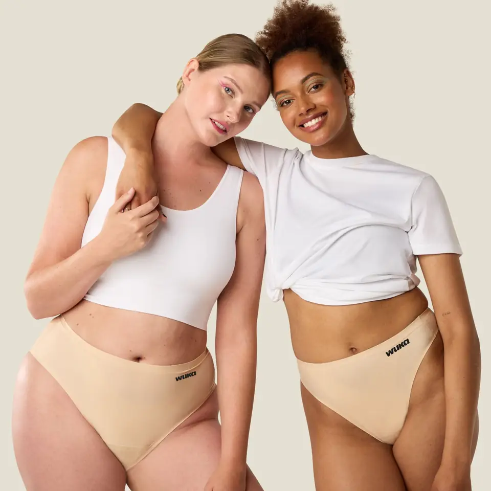 Two women in WUKA underwear and white tops, arms around each other