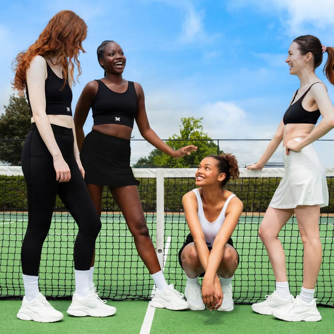 Four women in sportswear on a tennis court
