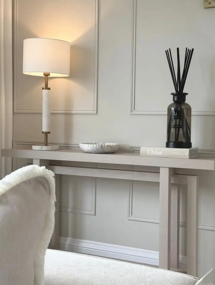 A black diffuser on a console table beside a lamp