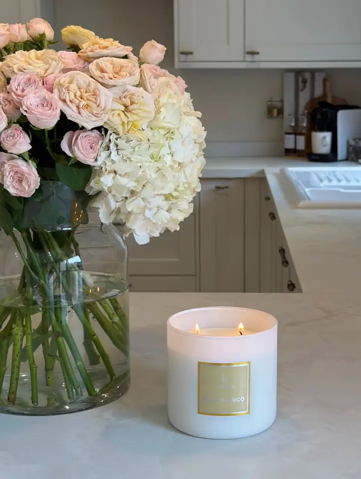 A candle and a vase of pink roses on a kitchen counter