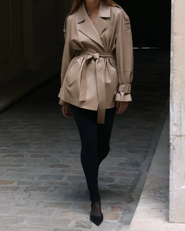 A model in a belted camel leather jacket walking down a Paris passage