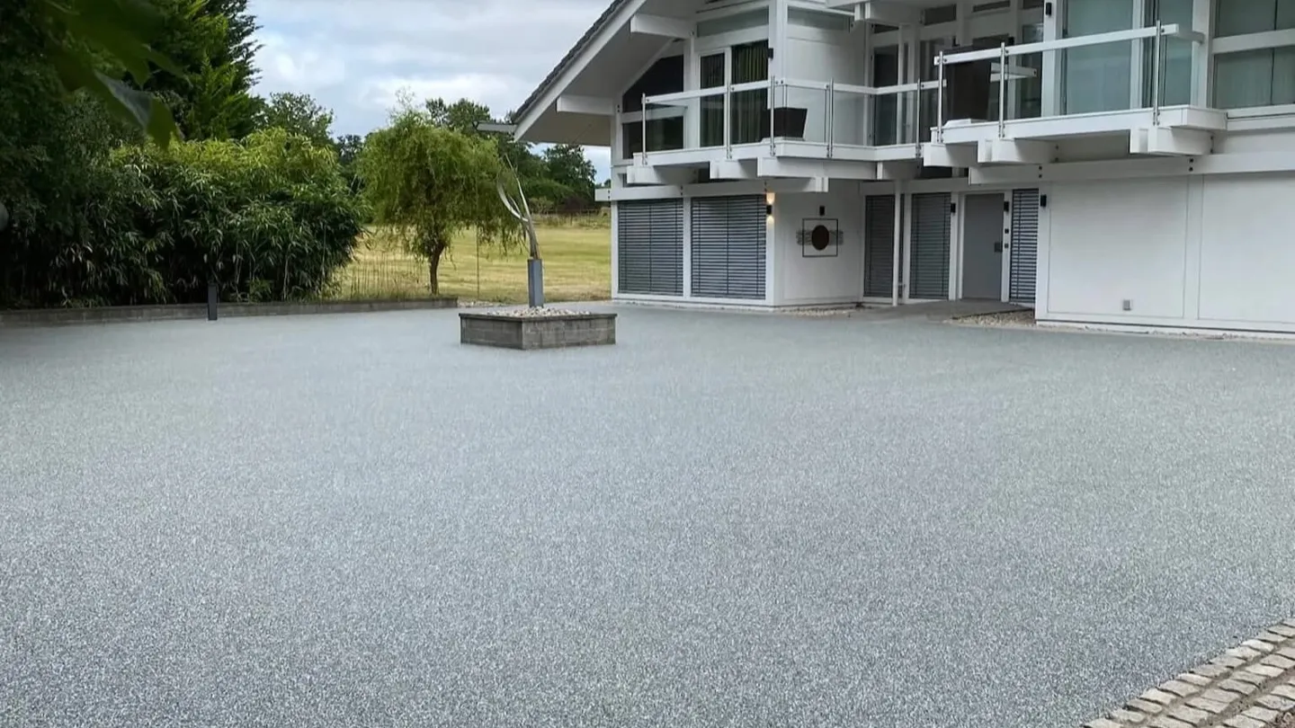 A resin-bound driveway laid by Smart Surfacing Solutions in front of a modern white house