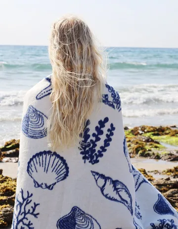 A shell-print throw from Cream Cornwall, worn on the Cornish coast